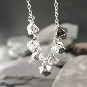 Seven mini polyhedral dice on a necklace, including a D4, D6, D100, D20, D8, D12 and aD10