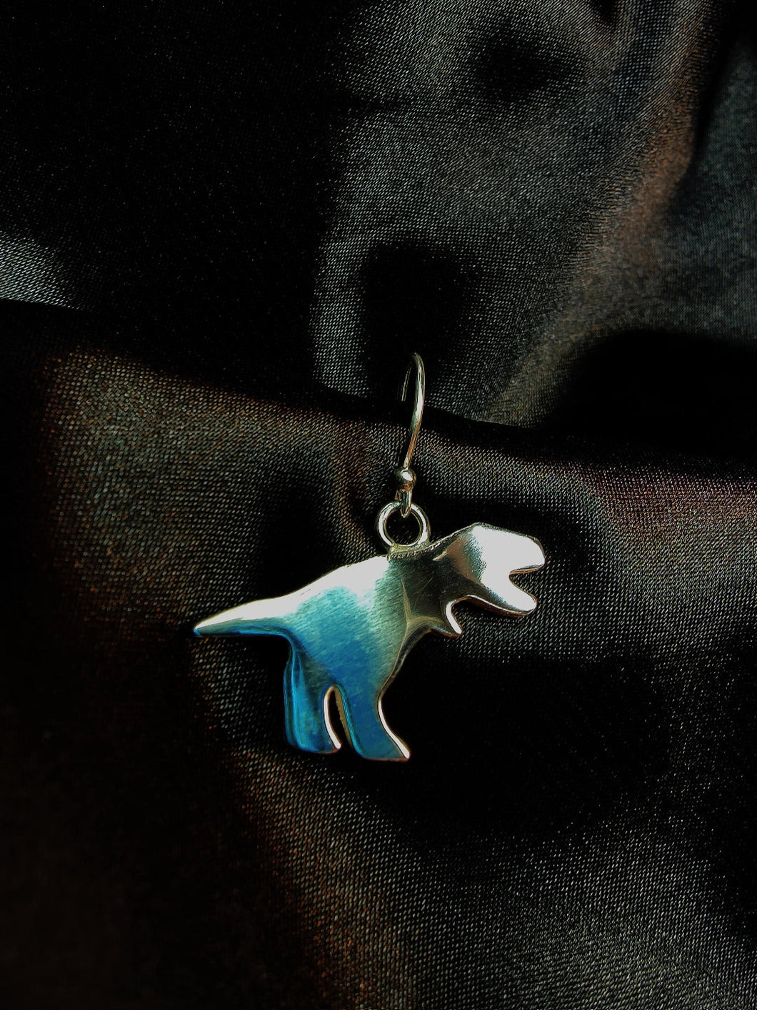 Cartoon style T-Rex made in silver presented on a silver hook earring.